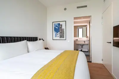 a bedroom with a white bed and a bathroom at PREMIER SUITES Amsterdam in Amsterdam