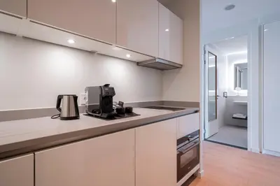 a kitchen with white cabinets and a coffee maker on the counter at PREMIER SUITES Amsterdam in Amsterdam