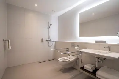 a white bathroom with a toilet and a sink at PREMIER SUITES Amsterdam in Amsterdam