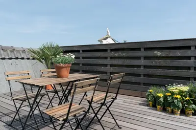 a wooden table and chairs on a deck with flowers at Empire suites roof terras in Amsterdam