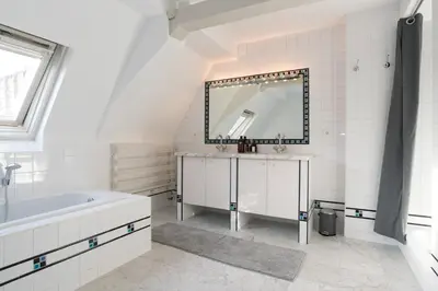a white bathroom with a tub and a mirror at Empire suites roof terras in Amsterdam