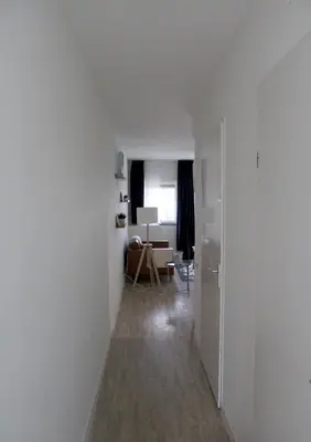 an empty room with a hallway with a chair and a desk at Landzicht in Woubrugge
