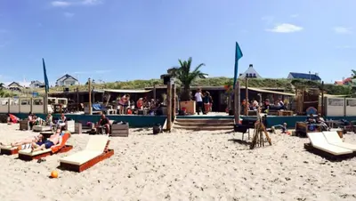 a group of people sitting on a beach at Sunset Lodge in Zandvoort