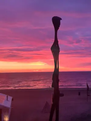 a statue of a woman on the beach with a sunset at Sunset Lodge in Zandvoort