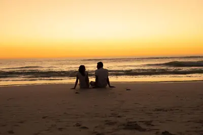 a couple sitting on the beach watching the sunset at Sunset Lodge in Zandvoort