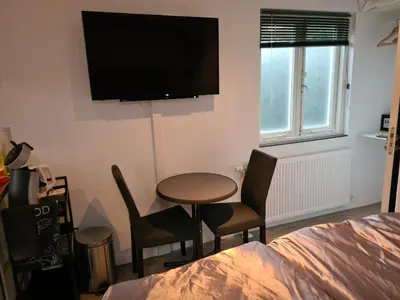a room with a table and chairs and a television on the wall at Sunset Lodge in Zandvoort