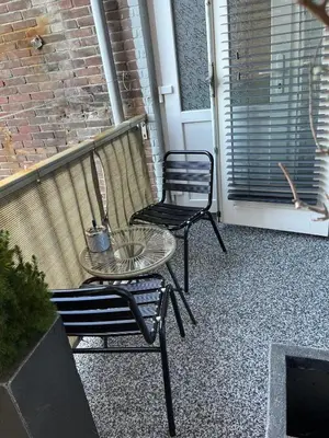 a patio with two chairs and a table and a door at Zaras Studios in Zandvoort