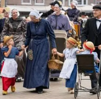 a woman and two children walking down a street with people at Huisje Finn, met grote tuin en veel privacy in Dirkshorn