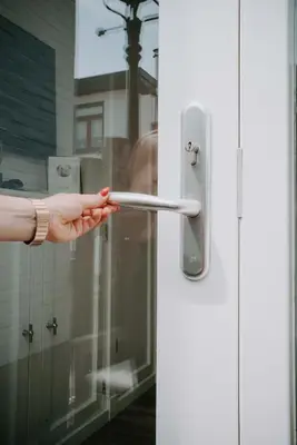 a person holding a door handle on a glass door at Tiny Beach House Zandvoort in Zandvoort