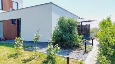 a garden in front of a white house with an umbrella at Luxury Suites Oosterwold in Almere