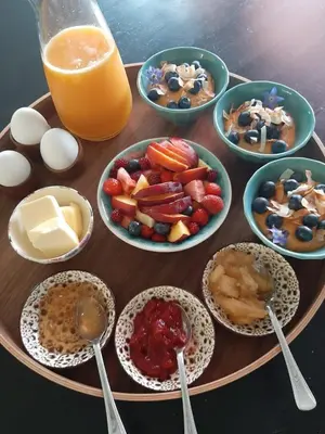 a table with plates of food and bowls of fruit and eggs at Luxury Suites Oosterwold in Almere
