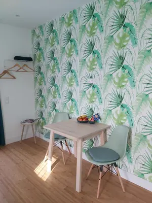 a dining room table and chairs with a tropical wallpaper at Luxury Suites Oosterwold in Almere
