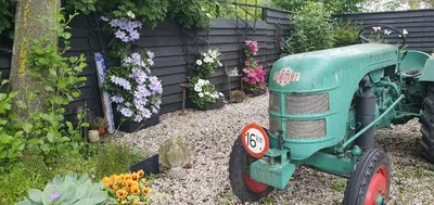 a green tractor sitting in a garden with flowers at Bed & breakfast FF rust in Kockengen