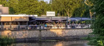 a restaurant with tables and umbrellas next to a river at Motor Yacht Almaz in Amsterdam