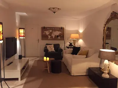 a living room with a white couch and a tv at Souterrain Zuid-Duinen -Free Parking in Zandvoort