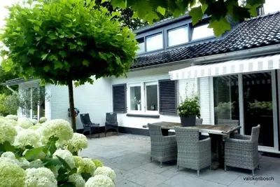 a patio with a table and chairs in front of a house at Bed and Breakfast Valckenbosch in Zeist