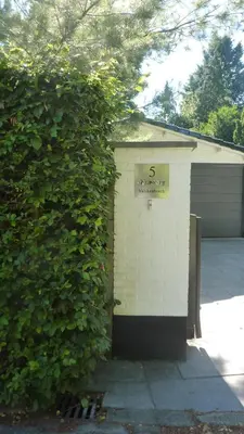 a building with the number on it next to a hedge at Bed and Breakfast Valckenbosch in Zeist