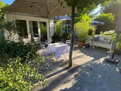 a patio with an umbrella and a table and chairs at Bed and Breakfast Valckenbosch in Zeist