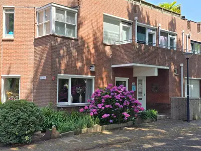 a brick building with purple flowers in front of it at House close to beach and city in Hoorn
