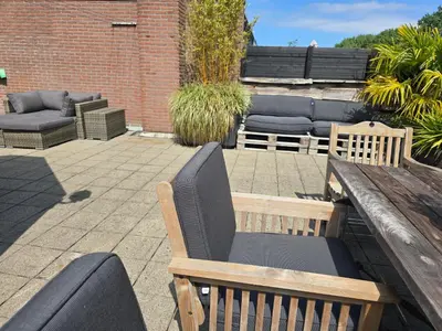 a patio with a wooden bench and a wooden table at House close to beach and city in Hoorn