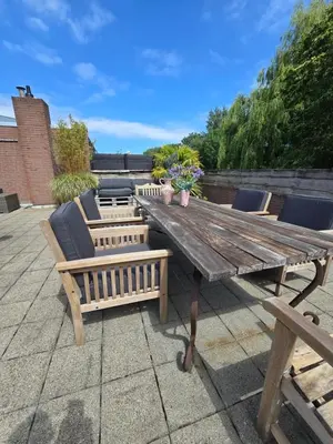 a wooden table and chairs on a patio at House close to beach and city in Hoorn