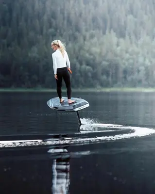 a woman standing on a surfboard in the water at Motor Yacht Amazone in Amsterdam