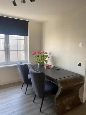a dining room with a table and chairs and a vase of flowers at Beach Studio in Zandvoort