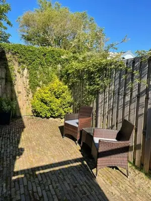 two benches sitting on a brick patio next to a fence at Studio River, Luxe dichtbij strand en Duinen in Egmond aan Zee