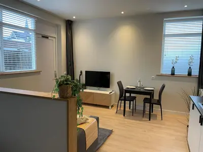 a living room with a table and a television at Studio River, Luxe dichtbij strand en Duinen in Egmond aan Zee