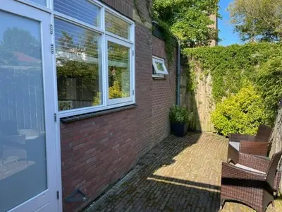 a brick building with two benches next to a door at Studio River, Luxe dichtbij strand en Duinen in Egmond aan Zee