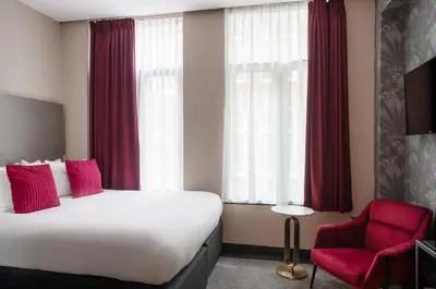 a hotel room with a bed and a red chair at Krisotel in Amsterdam