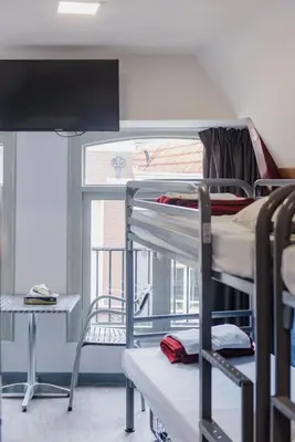 a dorm room with two bunk beds and a desk at Hostel Warmoes Amsterdam in Amsterdam
