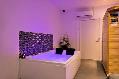 a purple room with a tub with two chairs at Wellness Suite Zeist in Zeist