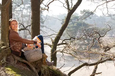 a woman sitting on a tree with a basket at 't Eekhoornnest in Soest