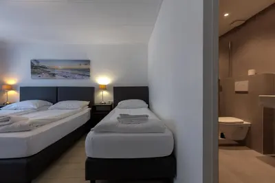 two twin beds in a room with a bathroom at Hotel Randenbroek in Amersfoort