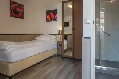 a bedroom with a bed and a glass shower at Hotel Randenbroek in Amersfoort