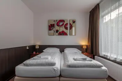 two white beds in a room with a window at Hotel Randenbroek in Amersfoort