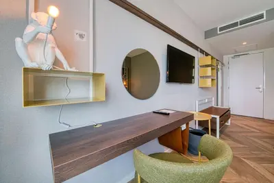 a room with a desk and a chair and a mirror at Vienna House Easy by Wyndham Amsterdam Airport Schiphol in Hoofddorp