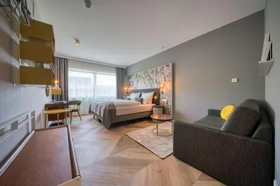 a hotel room with a bed and a couch at Vienna House Easy by Wyndham Amsterdam Airport Schiphol in Hoofddorp