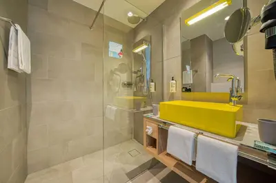 a bathroom with a yellow sink and a shower at Vienna House Easy by Wyndham Amsterdam Airport Schiphol in Hoofddorp
