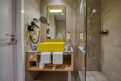 a bathroom with a yellow sink and a shower at Vienna House Easy by Wyndham Amsterdam Airport Schiphol in Hoofddorp