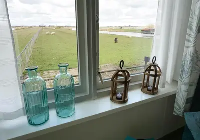 three glass bottles on a window sill with a view of a field at Welcome by Bianca in Jisp