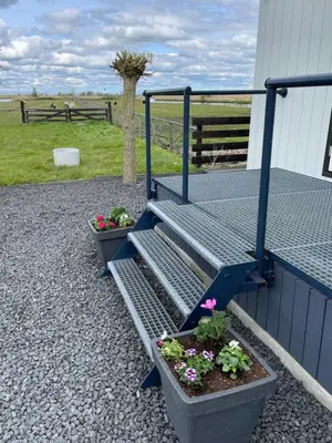 a metal bench with two potted plants next to a fence at Welcome by Bianca in Jisp