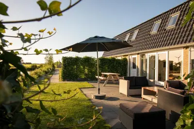 a patio with a table and an umbrella at Ruyge Weyde Logies - The Farmers Daughter in Oudewater