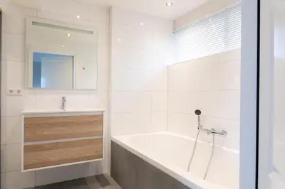 a white bathroom with a tub and a sink at Ruyge Weyde Logies - The Farmers Daughter in Oudewater