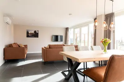 a dining room and living room with a table and chairs at Ruyge Weyde Logies - The Farmers Daughter in Oudewater