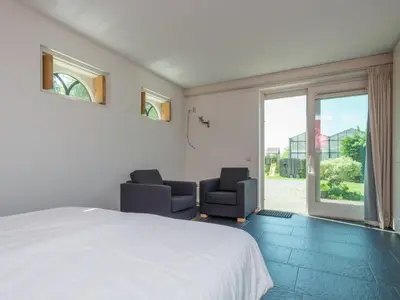 a bedroom with two chairs and a bed and a window at Haven with Garden & Comfort in Zuidoostbeemster