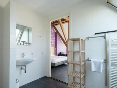 a bathroom with a sink and a toilet and a bathroom with a bed at Haven with Garden & Comfort in Zuidoostbeemster
