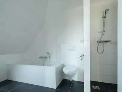 a white bathroom with a toilet and a bath tub at Haven with Garden & Comfort in Zuidoostbeemster