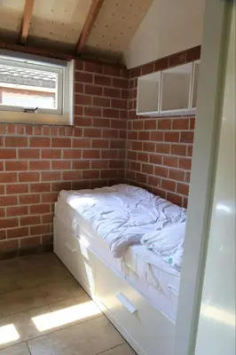 a bed in a room with a brick wall at Rekerlanden 98 in Schoorldam